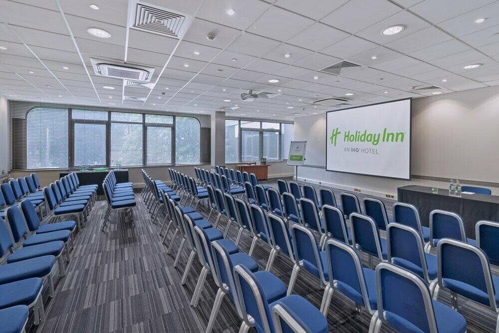 A meeting room at the hotel set out theatre style, with the Holiday Inn logo on the screen